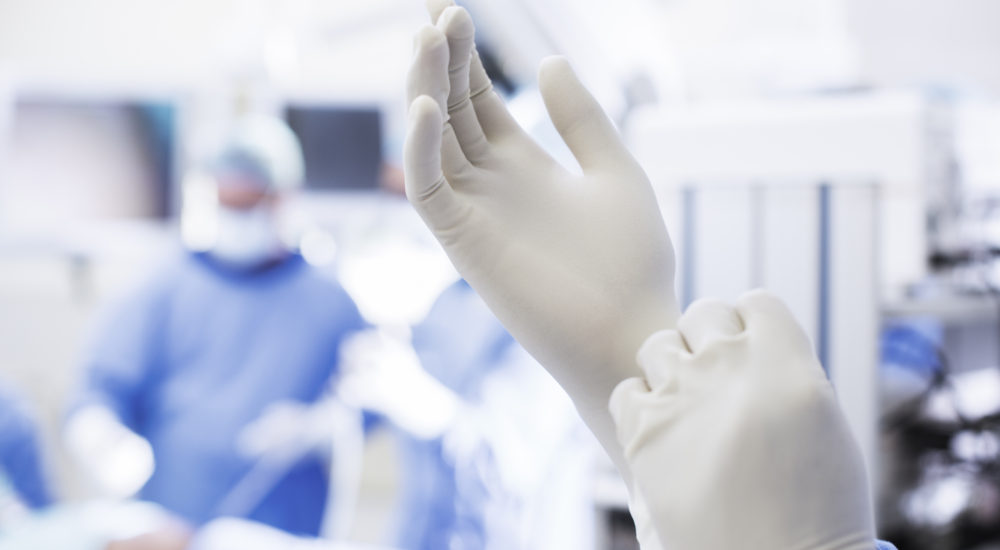 Close-up of surgeon putting on surgical gloves in operating theater